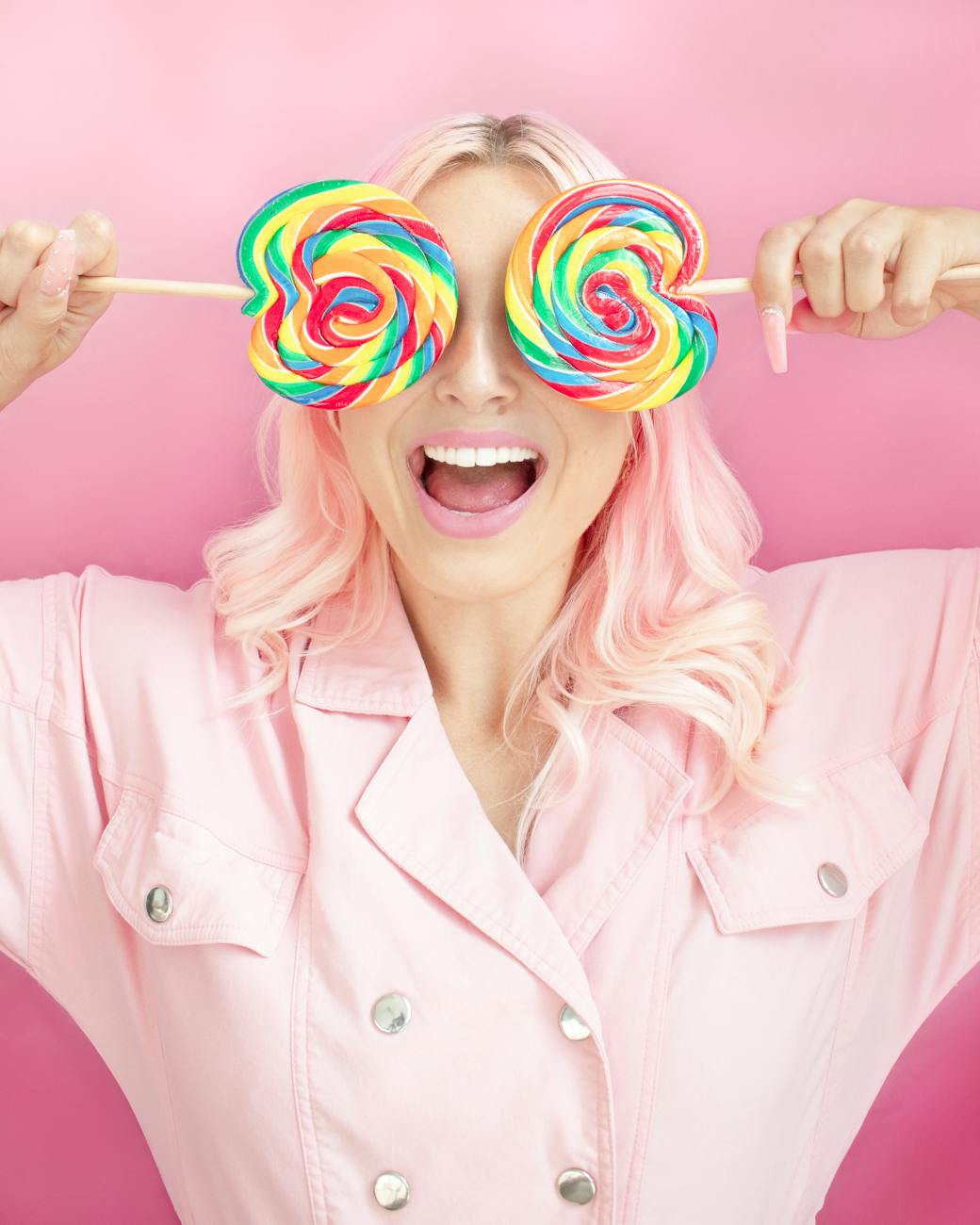 woman in pink button up shirt holding lollipops